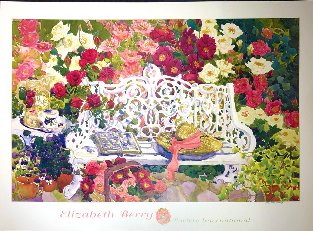 A white, floral style bench with red, pink and white flowers all around it. A straw hat with a pink ribbon and an open book rest on the bench. A pitcher and teacup rest on a small white table next to the bench. Dimensions: 33.5 inches by 23 inches