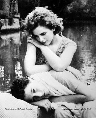 Black and white photo. A couple are near a pond. The young man lies in the woman's lap.