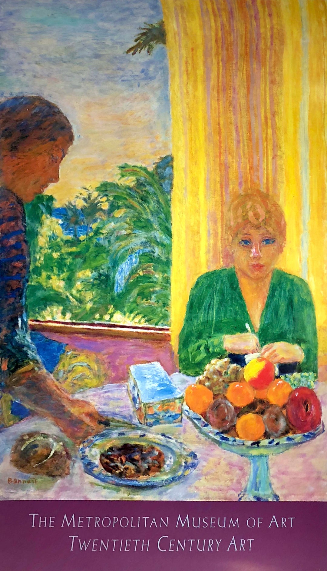 A woman in a green blouse sits in front of a yellow curtain. She is at a table covered with food. Someone comes by and places more food on the table. Lush bushes sit outside the window.