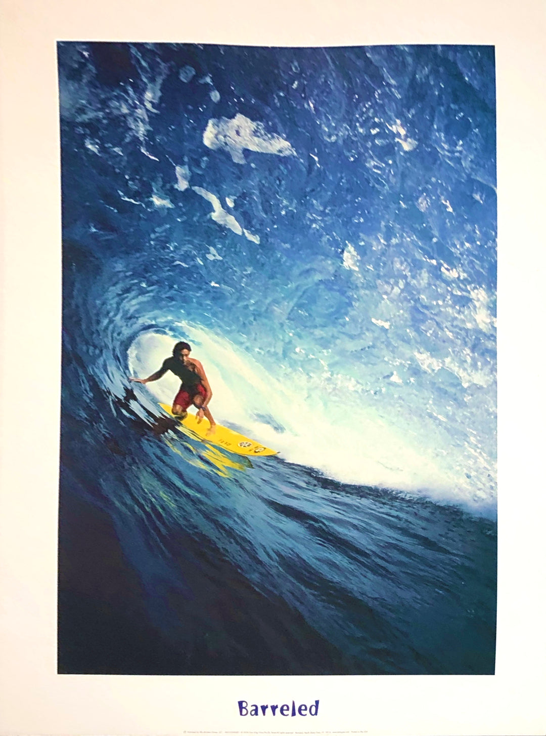 A tan man in red trunks surfs on a yellow surfboard. He surfs through a crashing blue wave.