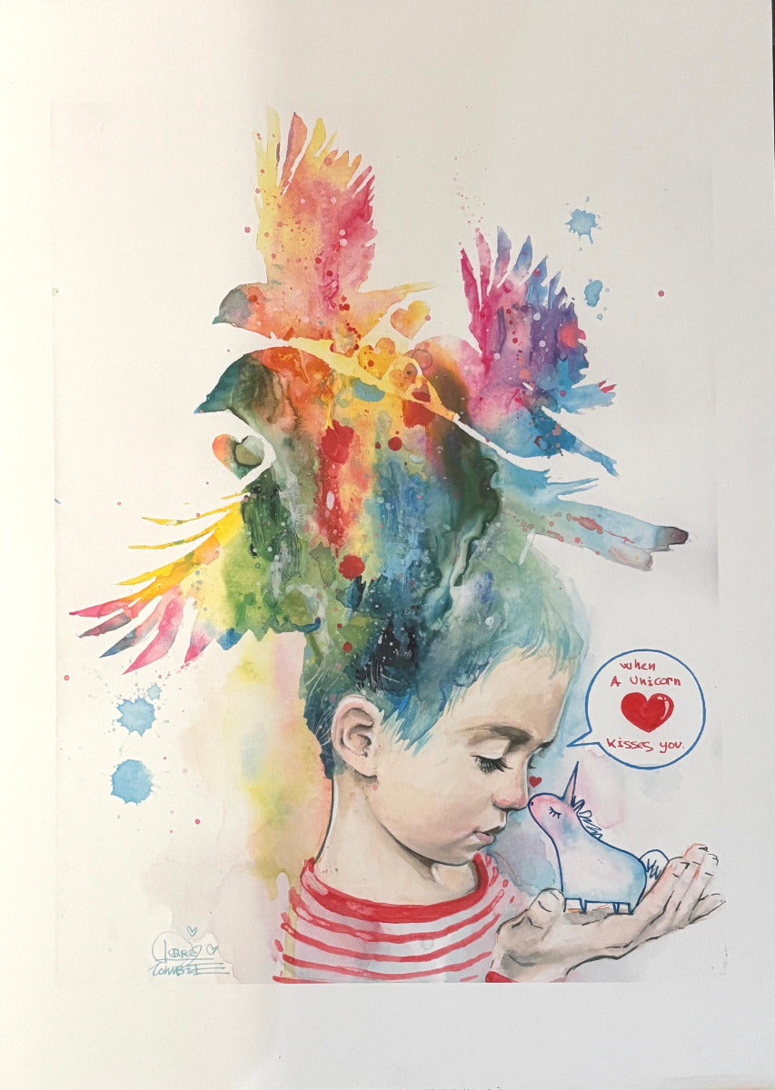 A colorful watercolor-style artwork showing a child in a red-and-white striped shirt holding a small pink creature, with birds and paint splashes rising above the head. The print is photographed against a white background.