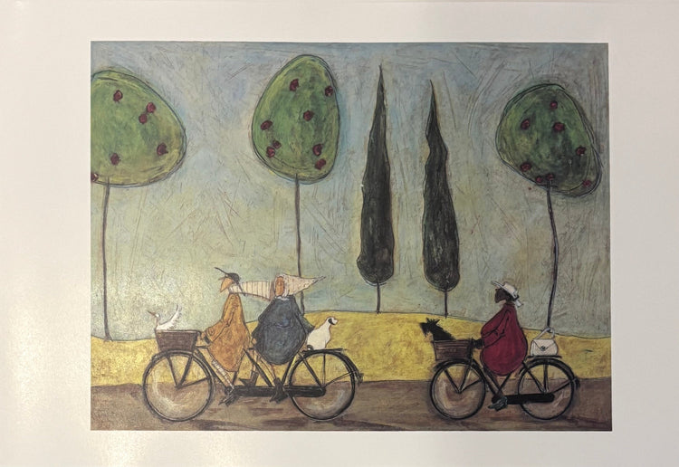 A square art print depicting a whimsical scene of two people riding bicycles with dogs, set against stylized trees and a pale blue sky, mounted on a white wall.