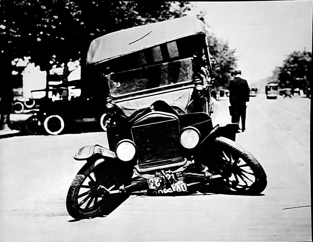 A broken down vintage car, its wheels in opposite directions.