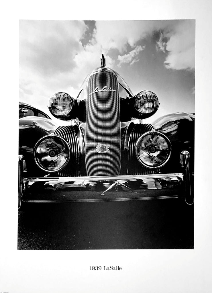 A black and white photo of a vintage car with a tall grill and four headlights. 