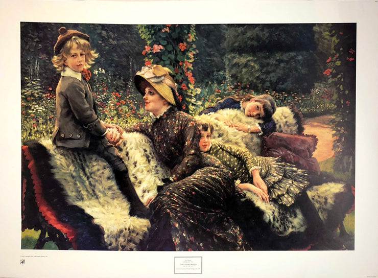 !800s children in their suits and dresses sit on a bench covered in a fur rug. The mother wears a sun hat and wears a black, floral dress. They are all in a garden.