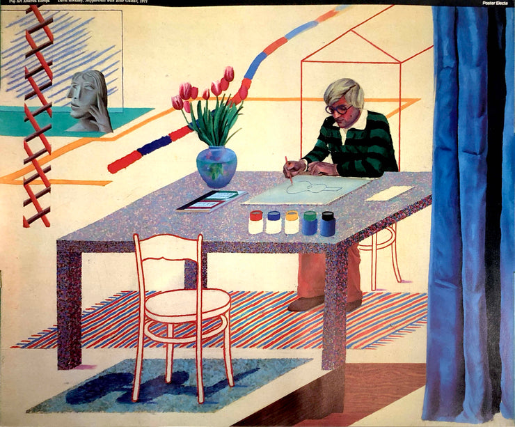 A Caucasian man with white hair and glasses in a green, striped shirt. He sits at a table with a vase with red flowers and paints with a tile in front of him. He is painting a blue guitar on it. A white chair sits across the able from him. A blue curtain hangs next to the table. Abstractions sit in the white background.