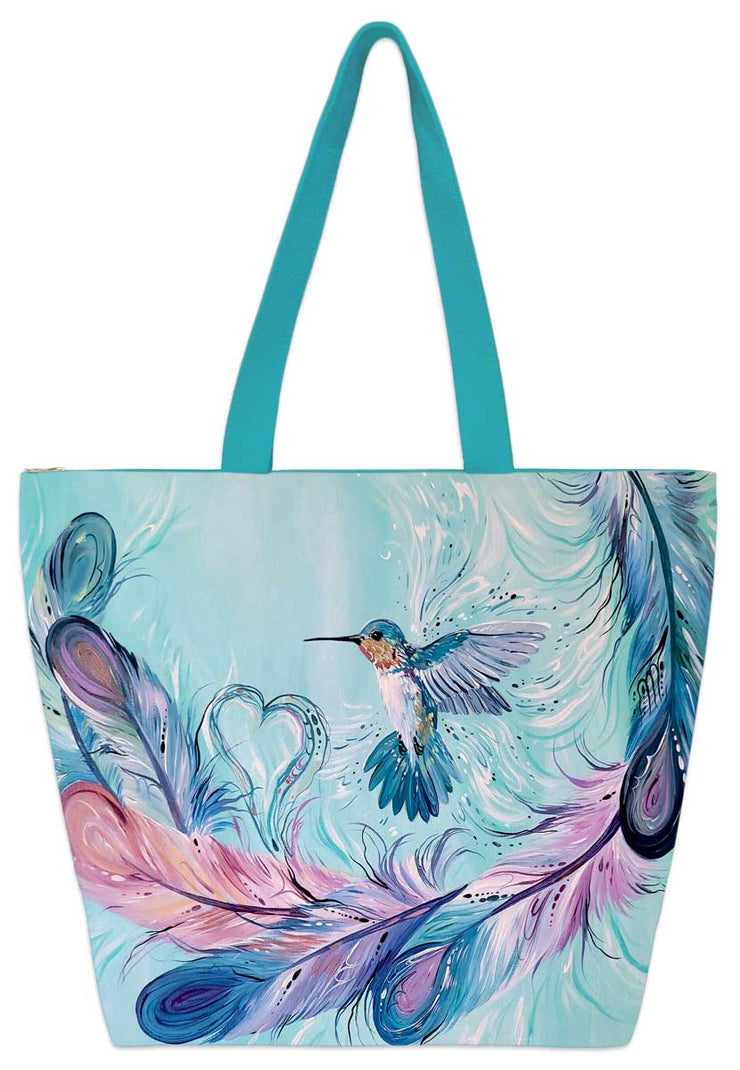 A humming bird flys around large feathers, a small heart forming from them. Set on a tote bag.