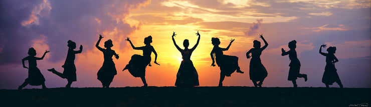 Nine dancers from a dance school in Kerala perform a choreography of the barath natyam called "jugalbandi," diversity in unity. They are silhouetted against the rising/setting sun. 
