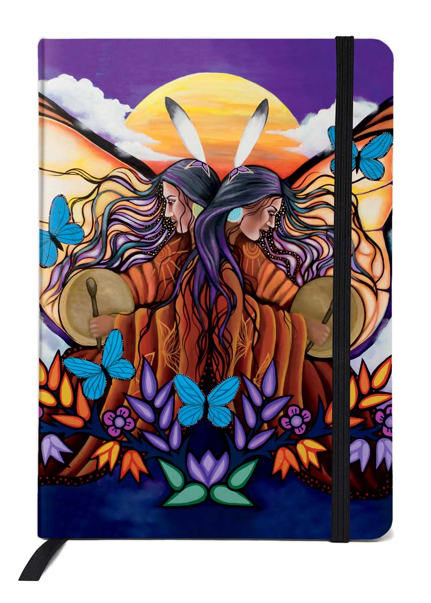 Two Indigenous women with a feather in her hair mirror each other. They both wear orange and play a drum. Butterflies flutter around them and two large butterfly wings spread out behind them. A sun hovers behind them. Printed on a journal.